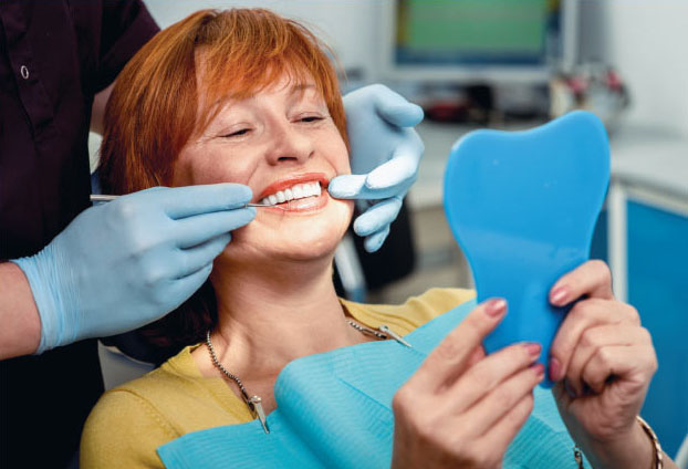 Woman looking at her smile in the mirror with dentist